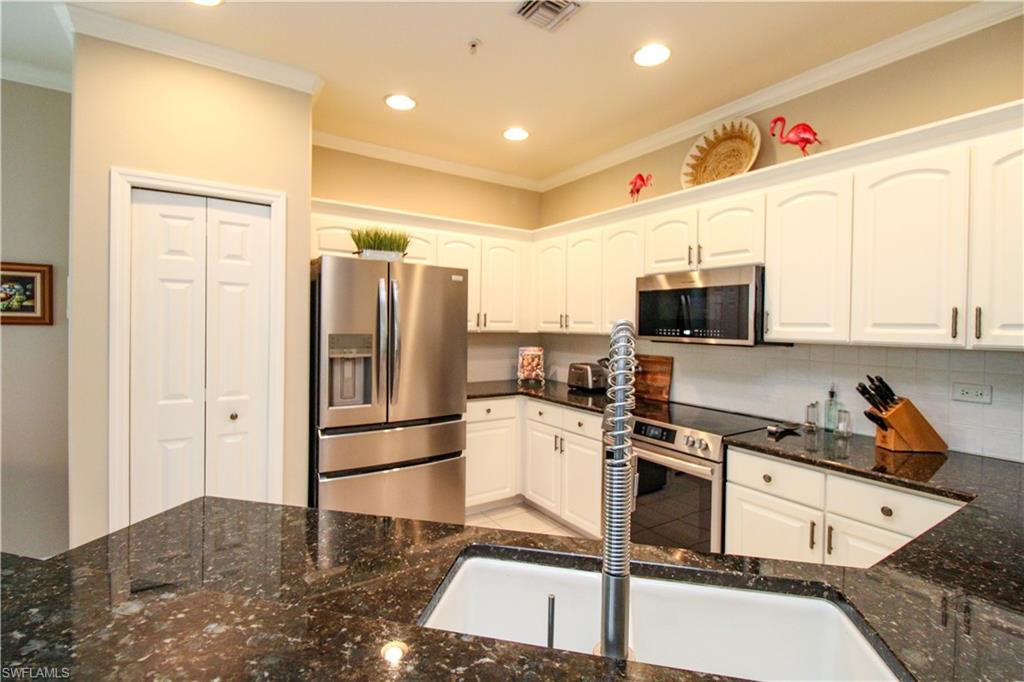 8488 Radcliffe Terrace, Unit 104 Naples, FL 34120 - Photo 12 of 50 a kitchen with stainless steel appliances granite countertop a refrigerator and a stove top oven