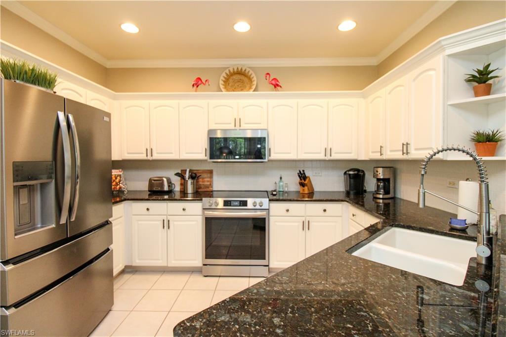 8488 Radcliffe Terrace, Unit 104 Naples, FL 34120 - Photo 15 of 50 a kitchen with stainless steel appliances granite countertop a sink stove refrigerator and cabinets