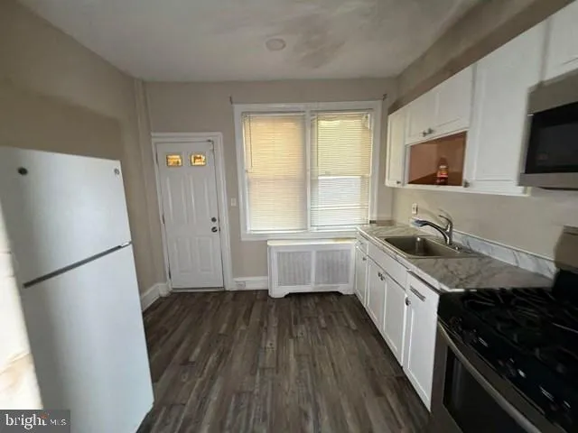 a kitchen with a sink a refrigerator a window and cabinets