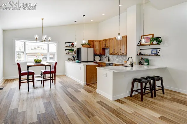 a kitchen with a table chairs wooden floors and a view of living room