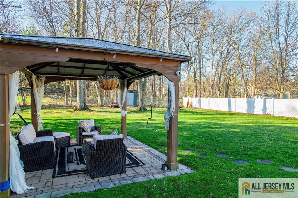 62 Laura Avenue Edison, NJ 08820 - Photo 12 of 35 a view of backyard with table and chairs under an umbrella with large trees
