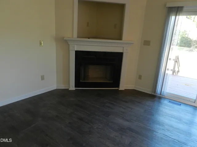 a view of empty room with wooden floor and fireplace