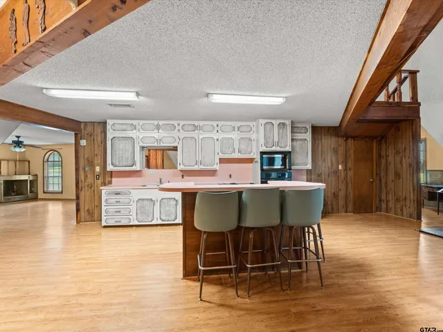 a living room with stainless steel appliances granite countertop furniture wooden floor and a kitchen view