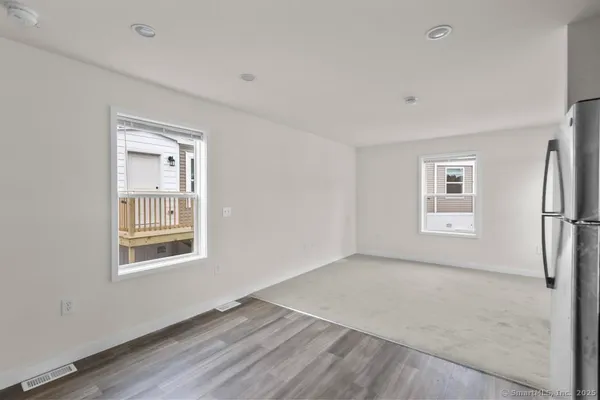 a view of an empty room with a window and wooden floor