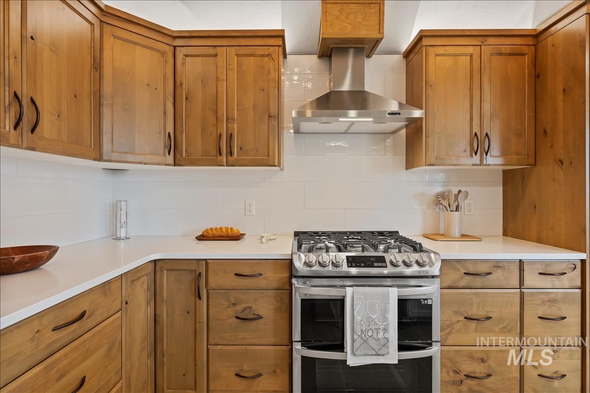79 East Aikens Road, Unit 202 Eagle, ID 83616 - Photo 16 of 47 Kitchen with double oven range, wall chimney range hood, brown cabinets, and tasteful backsplash