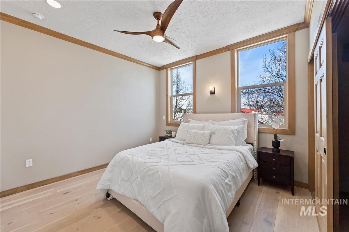 79 East Aikens Road, Unit 202 Eagle, ID 83616 - Photo 20 of 47 Bedroom featuring a textured ceiling, light wood-type flooring, ornamental molding, and a ceiling fan