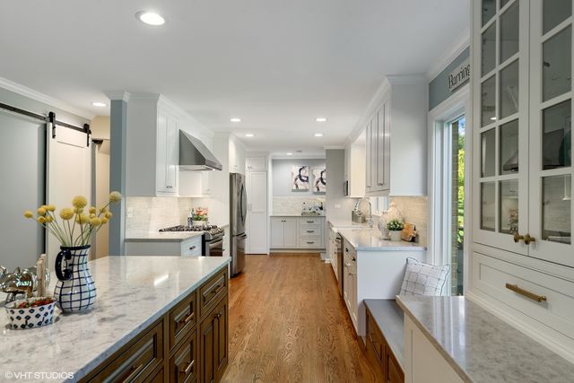 a large kitchen with granite countertop a large counter top appliances and cabinets