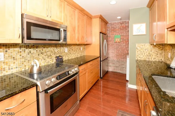 a kitchen with stainless steel appliances granite countertop a stove a sink and a microwave