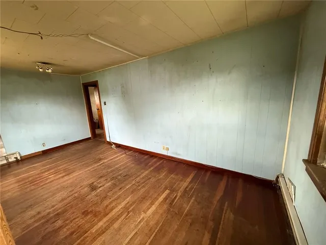 an empty room with wooden floor and cabinet