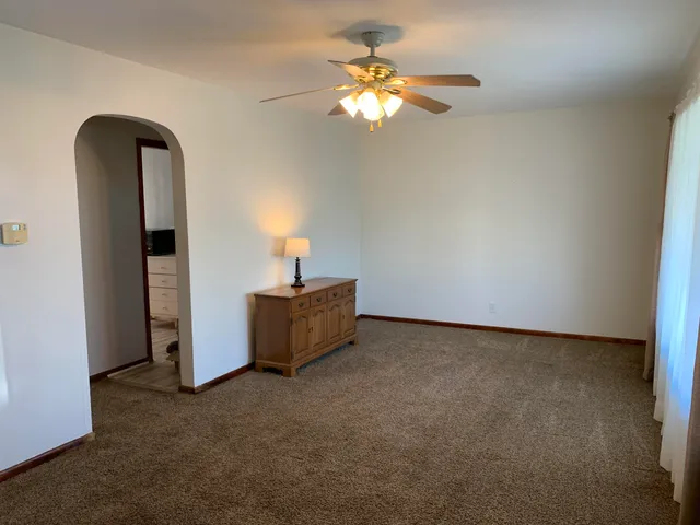 a view of an empty room with a chandelier fan
