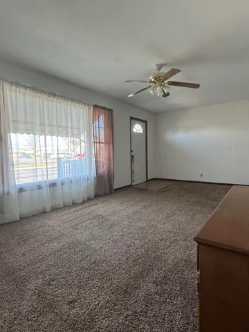 an empty room with windows and fan