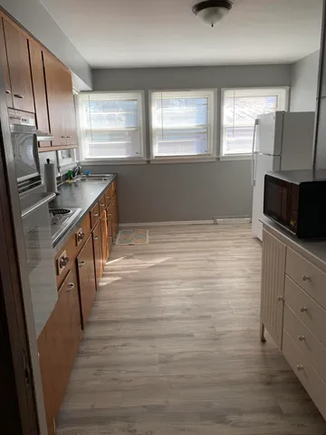 a kitchen with stainless steel appliances a sink a stove a microwave a window and a refrigerator