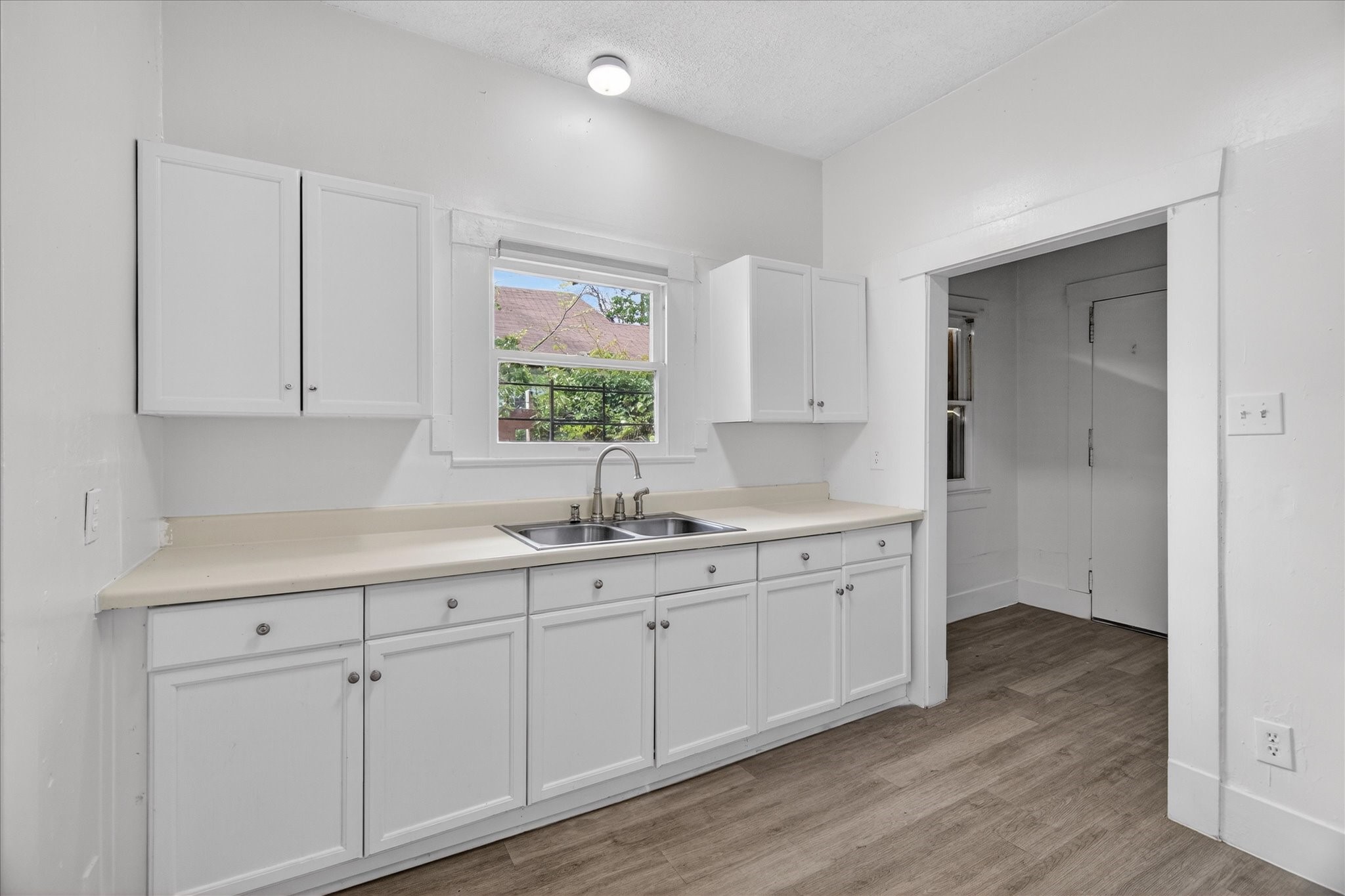 1607 Holman Street Houston, TX 77004 - Photo 11 of 24 a kitchen with white cabinets with sink and dishwasher with wooden floor