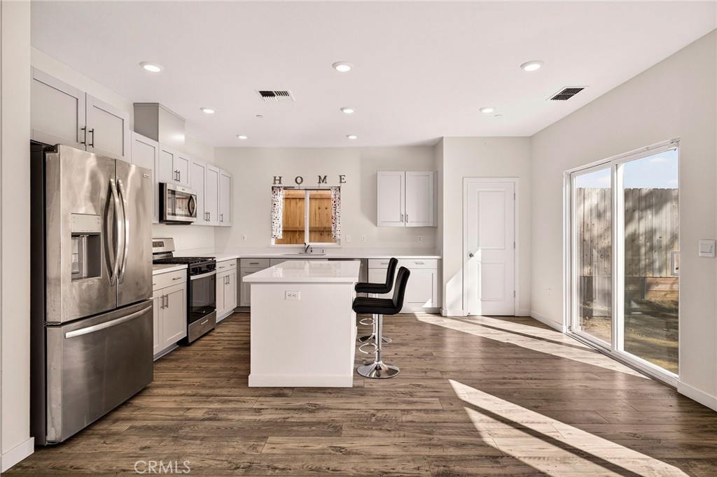 1147 Lentil Way Chico, CA 95928 - Photo 24 of 72 a kitchen with stainless steel appliances granite countertop a refrigerator a stove a sink dishwasher a dining table and chairs with wooden floor