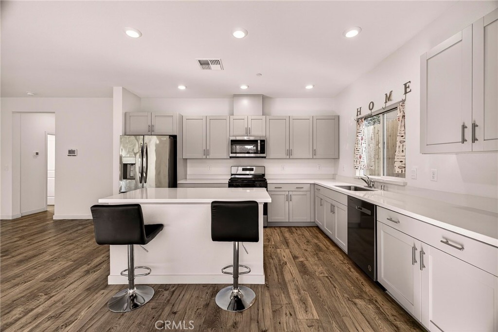 1147 Lentil Way Chico, CA 95928 - Photo 26 of 72 a kitchen with stainless steel appliances kitchen island granite countertop a stove top oven a sink dishwasher a refrigerator and a dining table with wooden floor