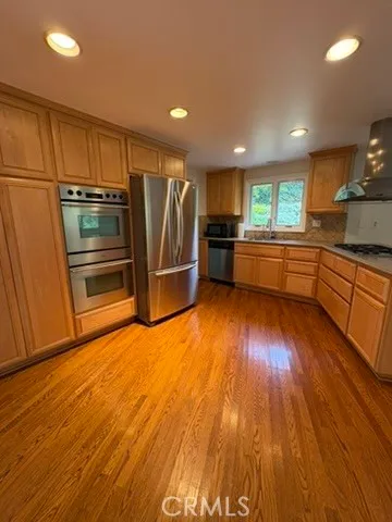 a kitchen with stainless steel appliances granite countertop a refrigerator a stove and a wooden floors