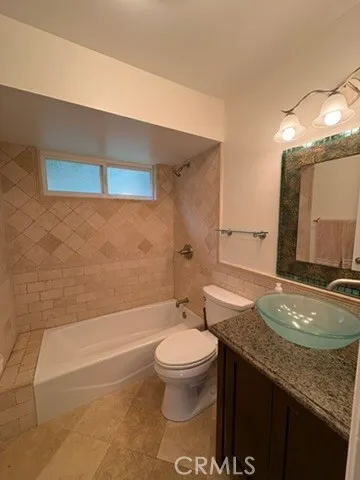 a bathroom with a granite countertop sink a toilet a mirror and bathtub
