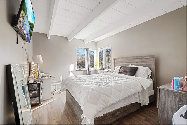 a bedroom with a large bed a potted plant and a dresser