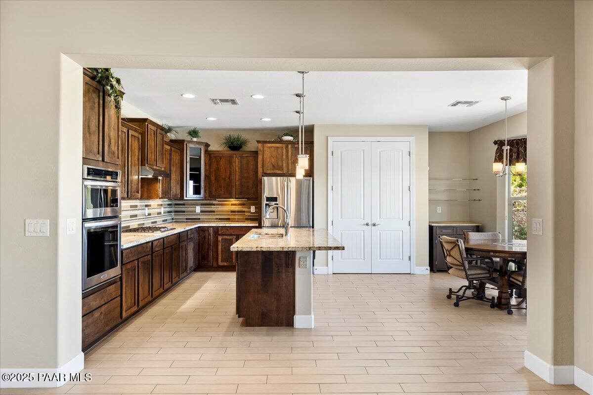 1149 Stack Rock Road Prescott Valley, AZ 86314 - Photo 12 of 85 a large white kitchen with stainless steel appliances kitchen island granite countertop a large kitchen island a stove and a sink