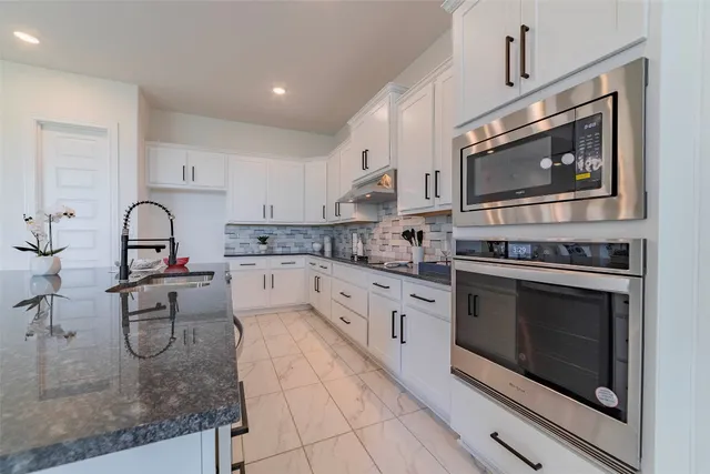a kitchen with stainless steel appliances granite countertop a stove and cabinets