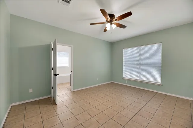 an empty room with chandelier fan and windows