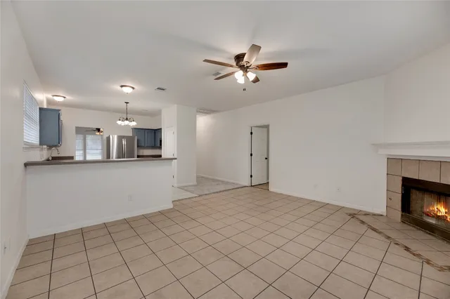 a view of an empty room and kitchen with fireplace