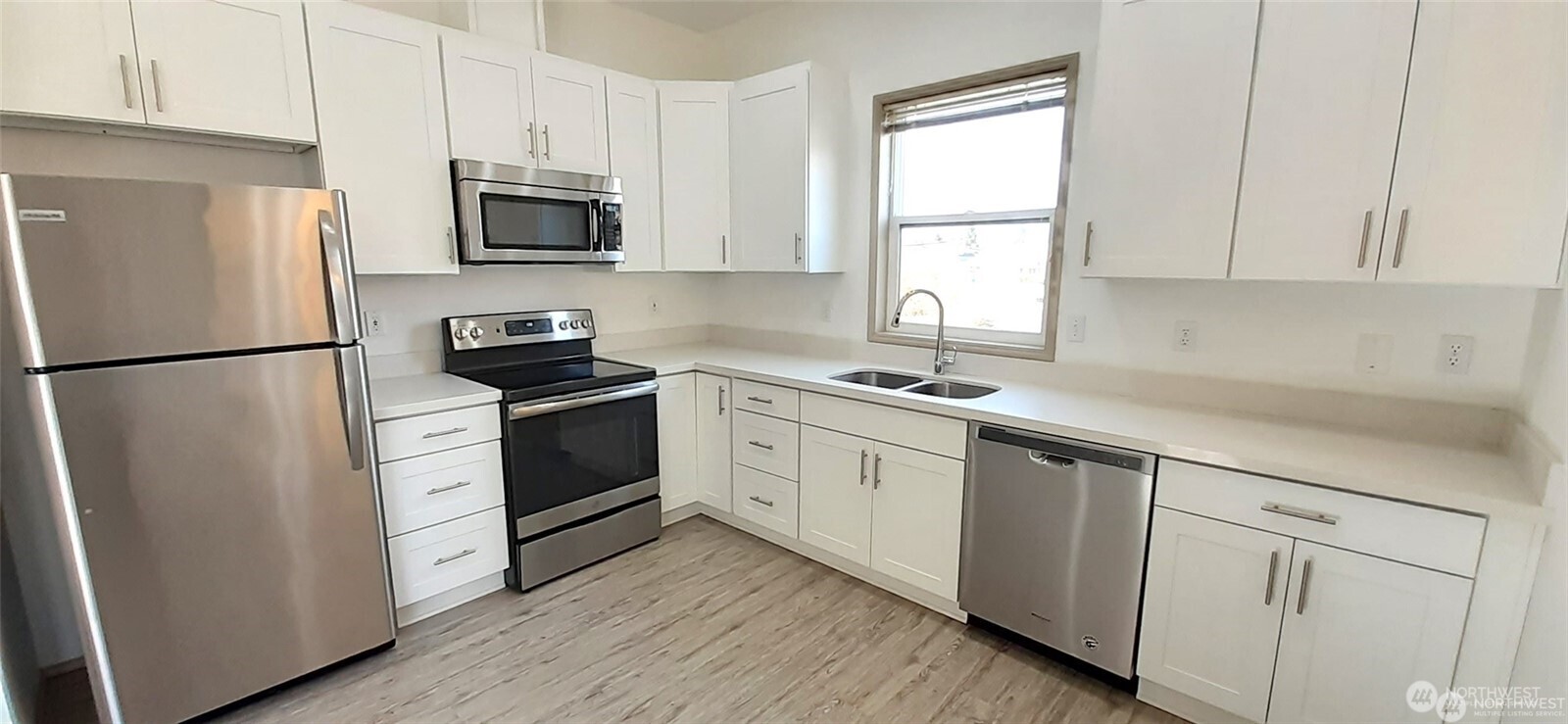 5501 Wilson Avenue South Seattle, WA 98118 - Photo 2 of 12 a kitchen with white cabinets stainless steel appliances a sink and a window