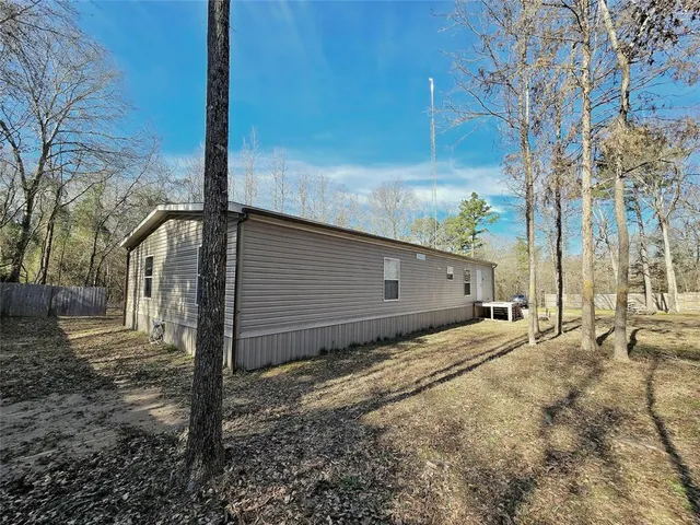 a backyard of a house with large trees and wooden fence