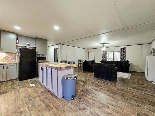 a kitchen with granite countertop a refrigerator and a wooden cabinets