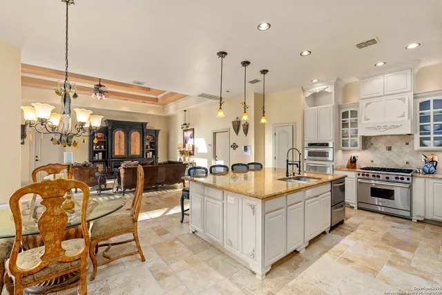 a kitchen with stainless steel appliances kitchen island granite countertop a table chairs and a stove