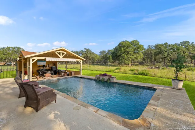 a view of swimming pool with seating area and trees in the background