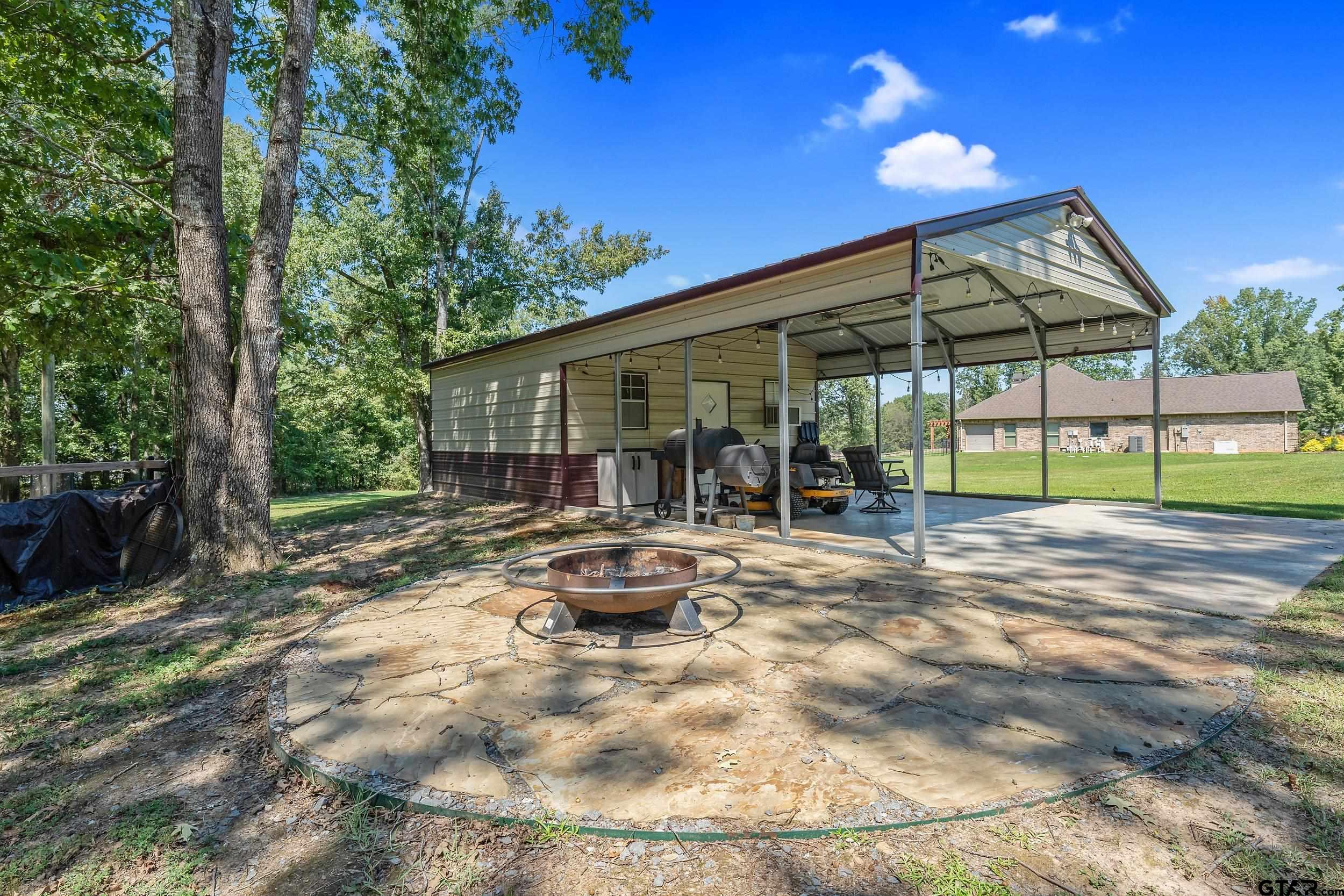 140 Creek Drive Marshall, TX 75672 - Photo 29 of 35 a view of a backyard with table and chairs under an umbrella