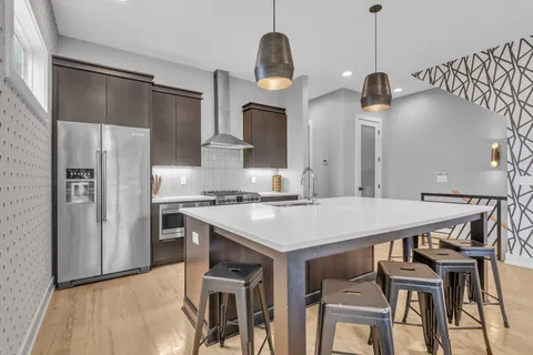 a kitchen with stainless steel appliances granite countertop a sink a stove a refrigerator and a stove