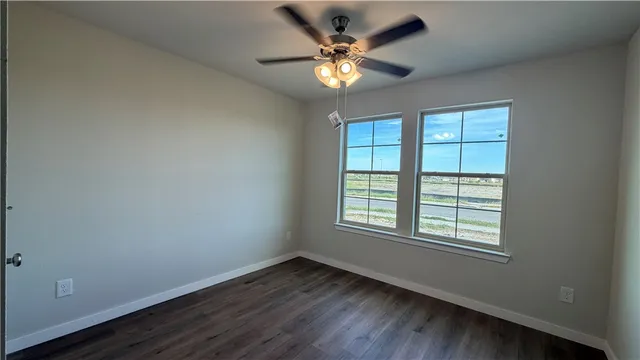 a view of an empty room with window and wooden floor