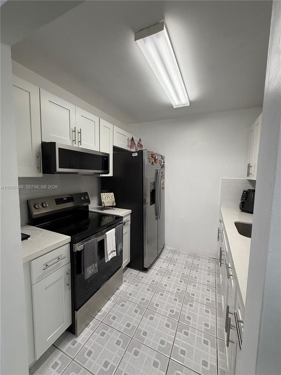 200 Southwest 132nd Way, Unit 109L Pembroke Pines, FL 33027 - Photo 2 of 18 a kitchen with granite countertop a refrigerator and a stove