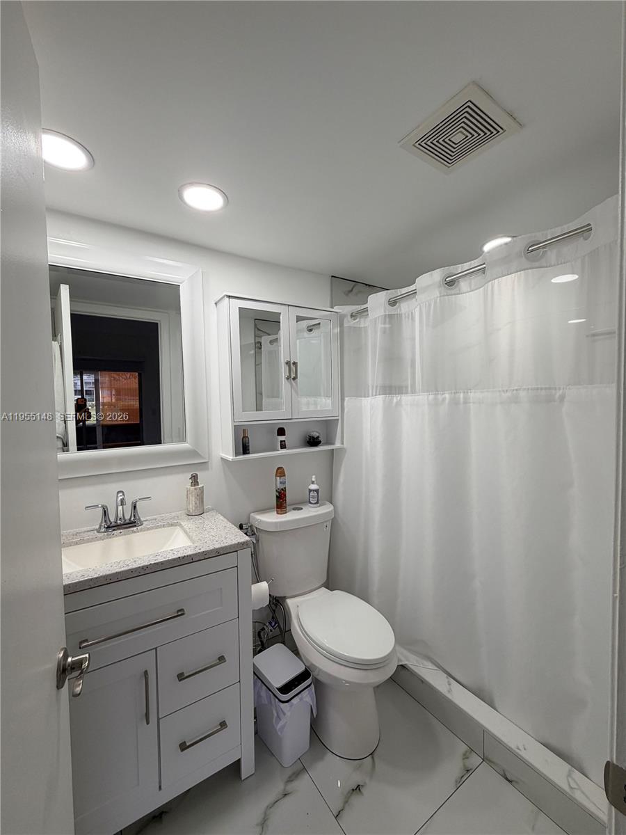 200 Southwest 132nd Way, Unit 109L Pembroke Pines, FL 33027 - Photo 8 of 18 a bathroom with a toilet sink a mirror and vanity