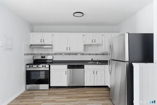 a kitchen with granite countertop a refrigerator and a stove top oven