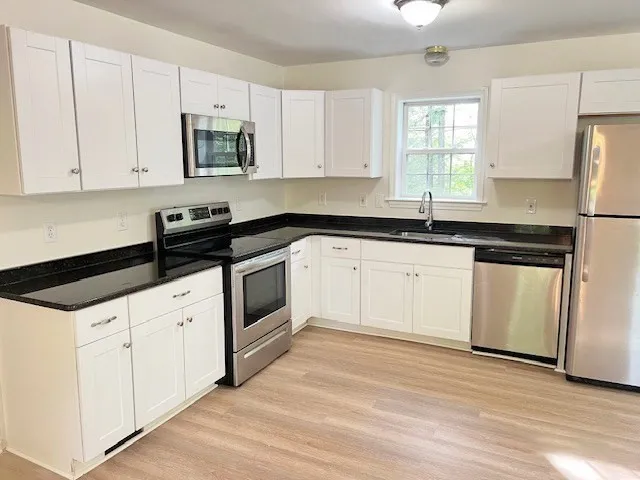 a white kitchen with granite countertop white cabinets and white appliances