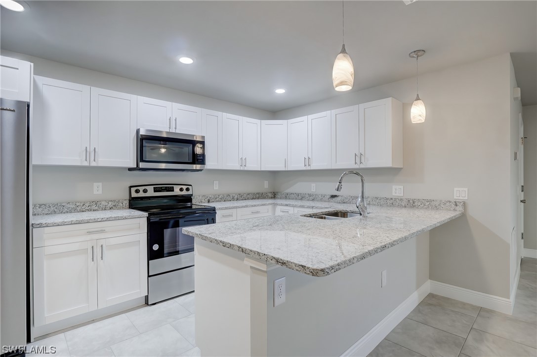 3215 46th Street West Lehigh Acres, FL 33971 - Photo 11 of 50 a kitchen with a sink a stove a microwave and cabinets