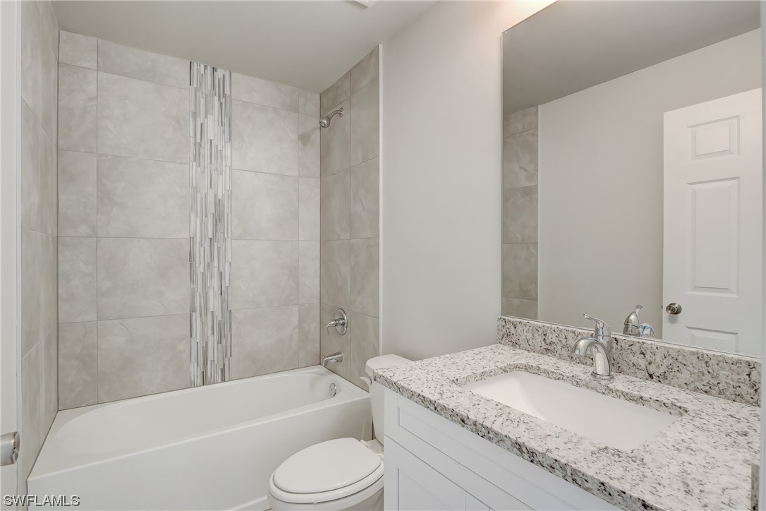 3215 46th Street West Lehigh Acres, FL 33971 - Photo 23 of 50 a bathroom with a granite countertop bathtub shower sink vanity mirror and toilet