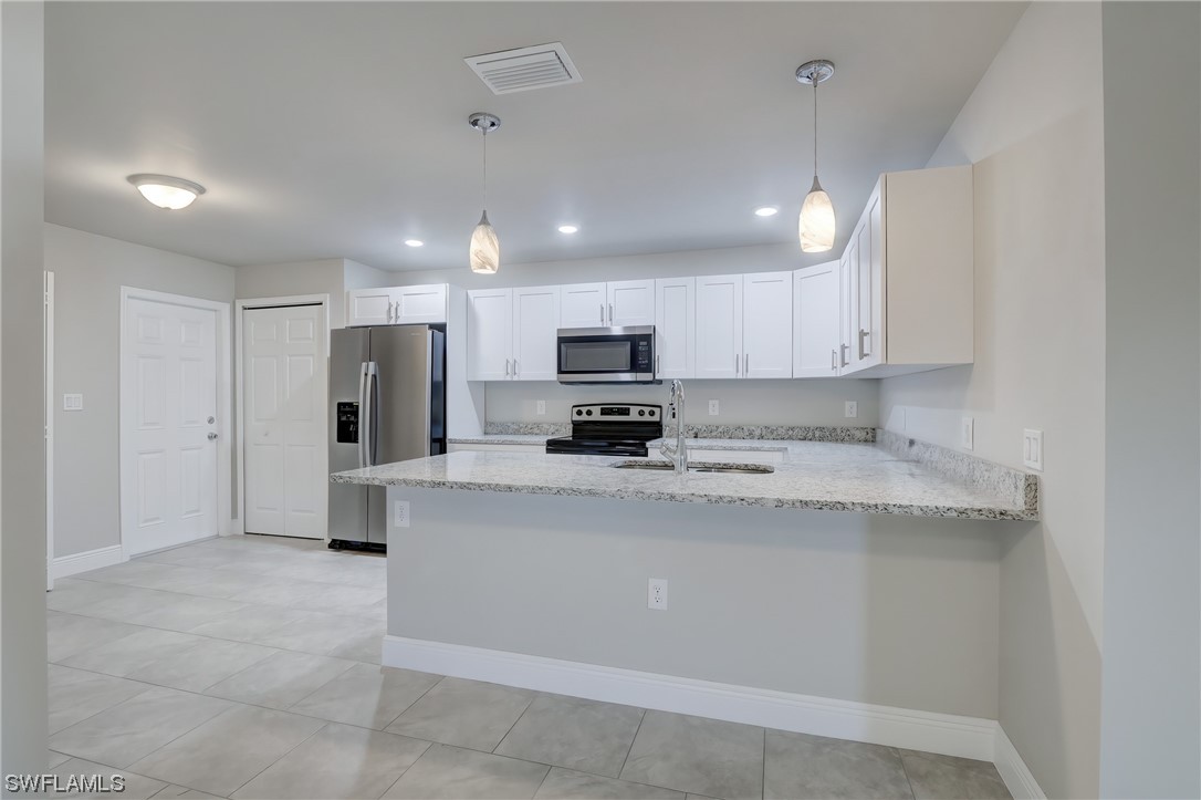 3215 46th Street West Lehigh Acres, FL 33971 - Photo 10 of 50 a kitchen with stainless steel appliances granite countertop a refrigerator sink and cabinets