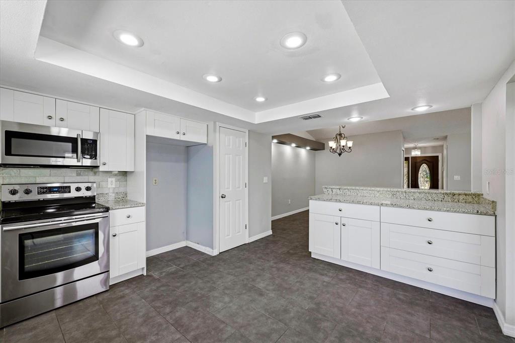 12836 Pineway Drive Largo, FL 33773 - Photo 4 of 28 a kitchen with granite countertop white cabinets and stainless steel appliances