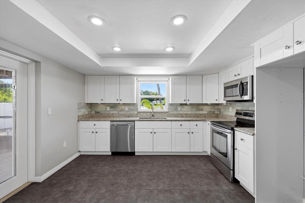12836 Pineway Drive Largo, FL 33773 - Photo 6 of 28 a kitchen with granite countertop cabinets stainless steel appliances a sink and a window