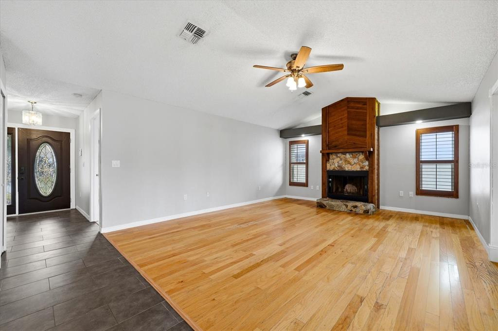 12836 Pineway Drive Largo, FL 33773 - Photo 9 of 28 a view of empty room with a fireplace and wooden floor