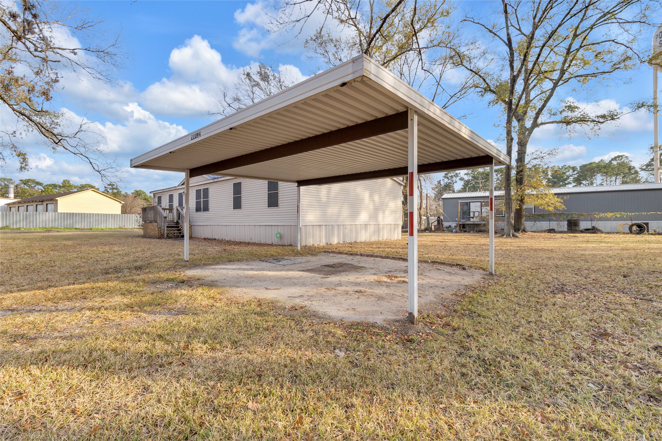 22094 Spear Road Porter, TX 77365 - Photo 36 of 45 Metal carport in a spacious yard. The area is open and grassy, ideal for outdoor activities.