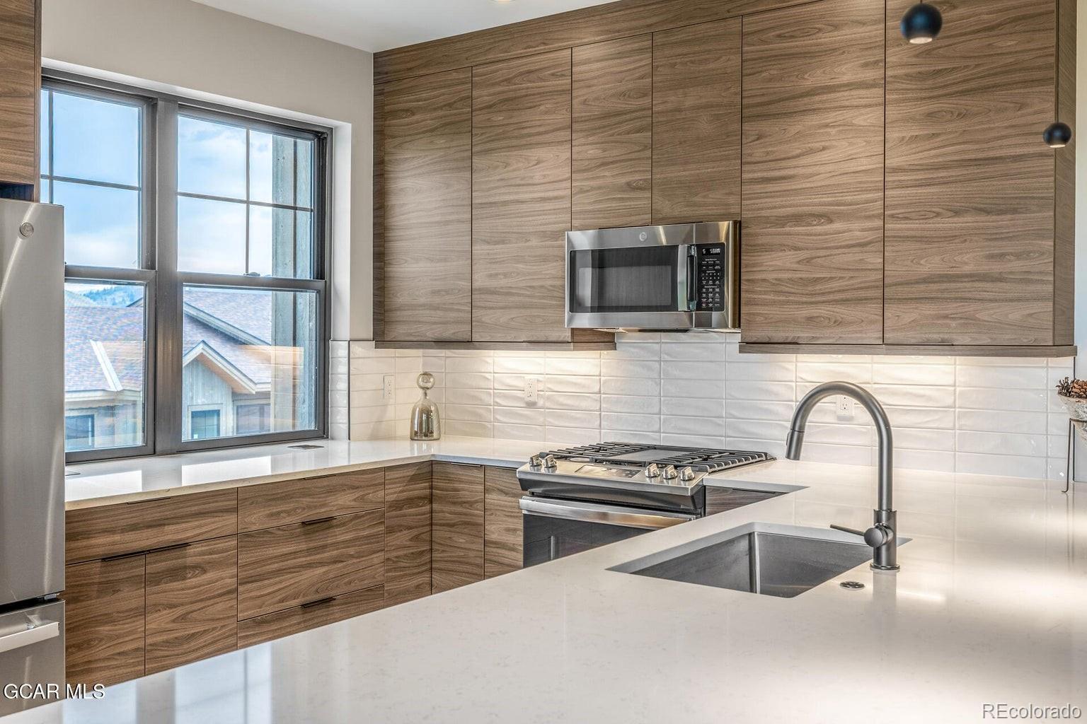 104 Saddle Mountain Camp Road Granby, CO 80446 - Photo 22 of 50 a kitchen with granite countertop a sink and a stove next to a window