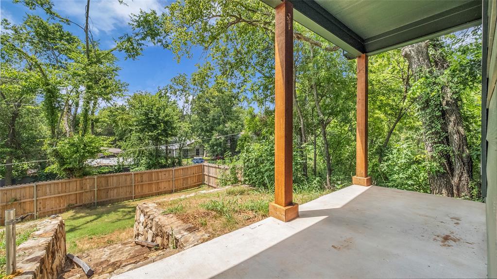 716 East Chestnut Street Denison, TX 75021 - Photo 24 of 26 Covered concrete patio with natural wood support beams and a dark green ceiling, overlooking a fenced backyard with mature trees