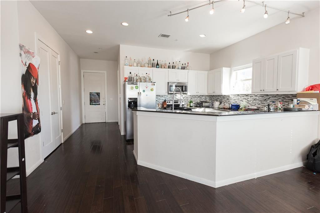 2708 San Pedro Street, Unit 302 Austin, TX 78705 - Photo 2 of 11 a kitchen with stainless steel appliances granite countertop a refrigerator a sink dishwasher a stove and white countertops with wooden floor
