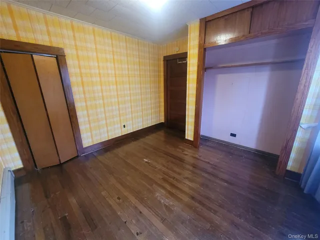 an empty room with wooden floor and entrance