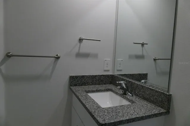 a bathroom with a granite countertop sink and a mirror